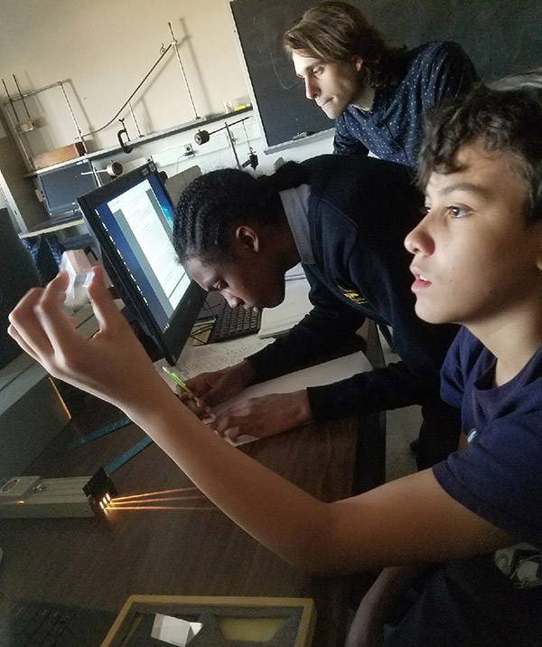 Michael inspects a transparent lens before using it to study the bending of light